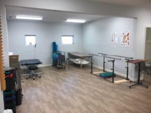 Physical Therapy clinic treatment area with table and balance bars gym area