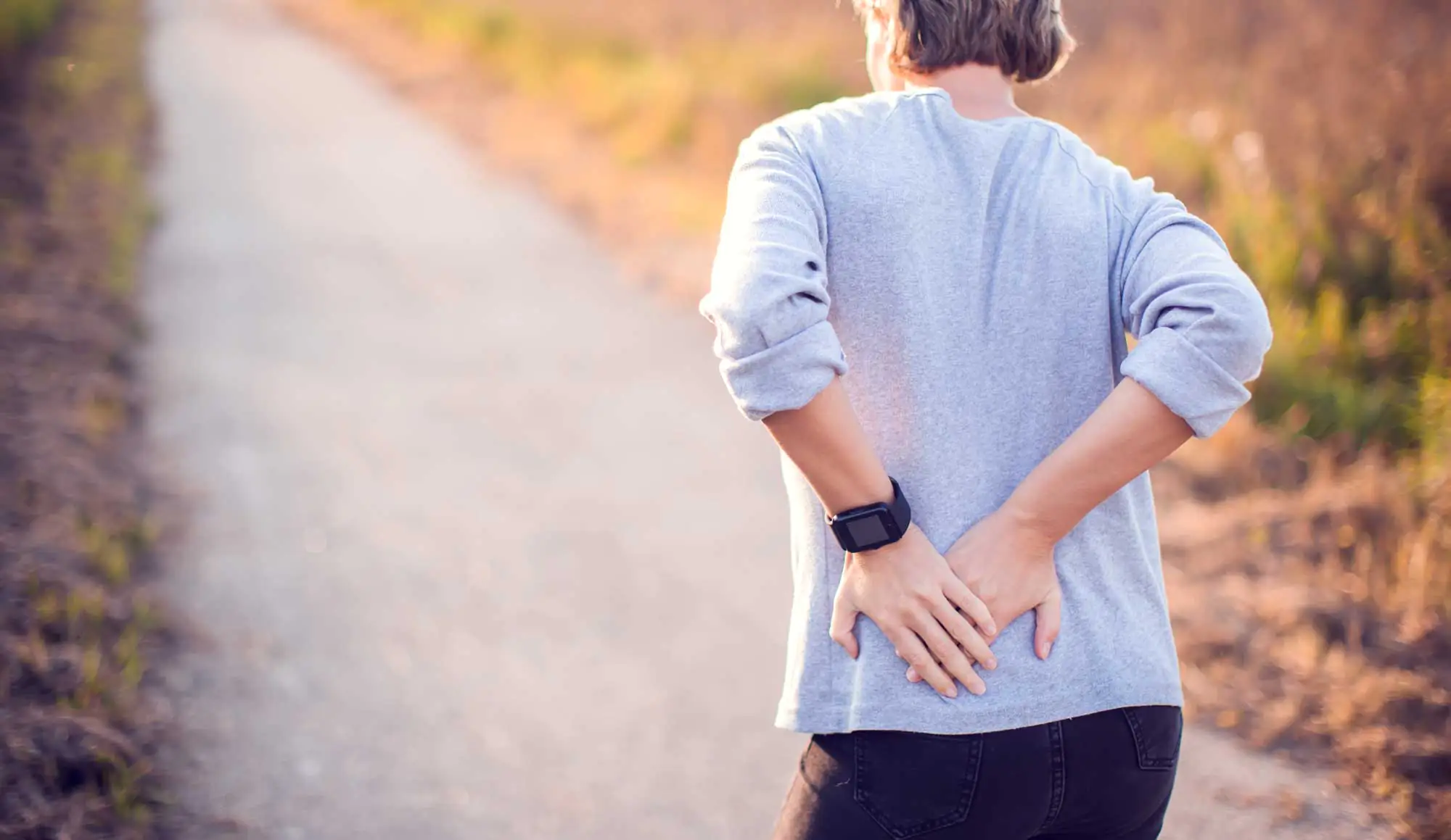 People, healthcare and problem concept - woman suffering from pain in back or reins outdoor